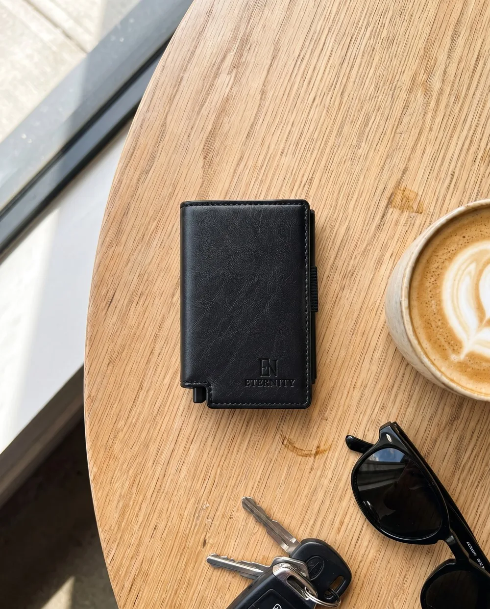 Eternity op een cafétafel naast een flat white, sleutels en een zonnebril